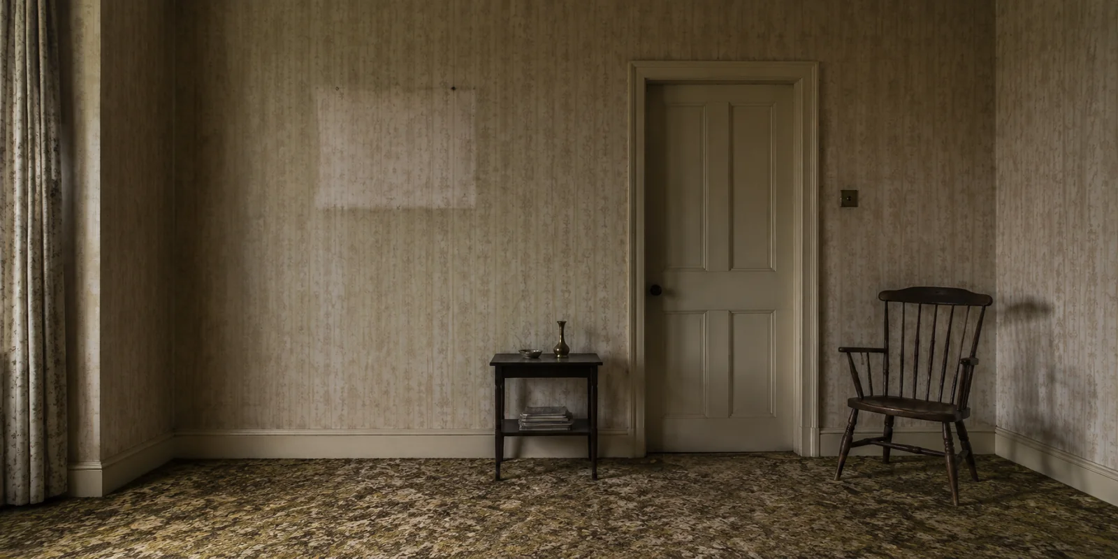 An empty, timeworn sitting room with a chair and a closed door.